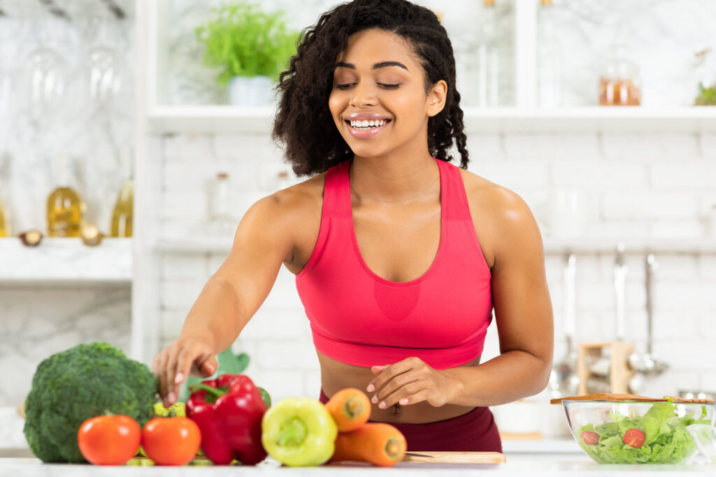 the woman in the kitchen looks at the vegetables with a smile