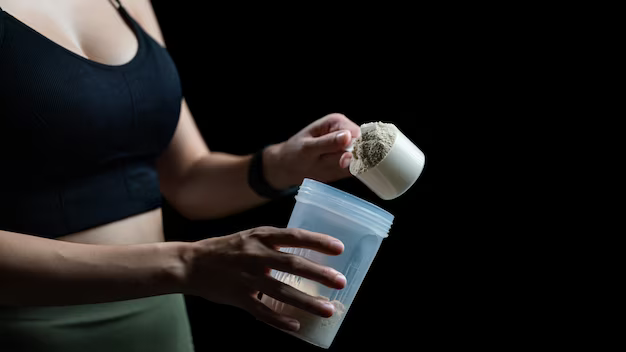 Close-up of woman with protein measuring spoon and shaker