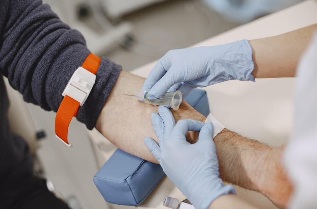 a man donates blood in a hospital, a nurse gives an injection in the arm