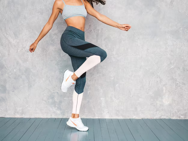 Girl jumping in the studio near a gray wall