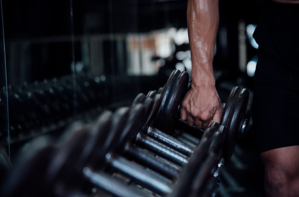 the hand of a sportsman lifting a barbell in the gym